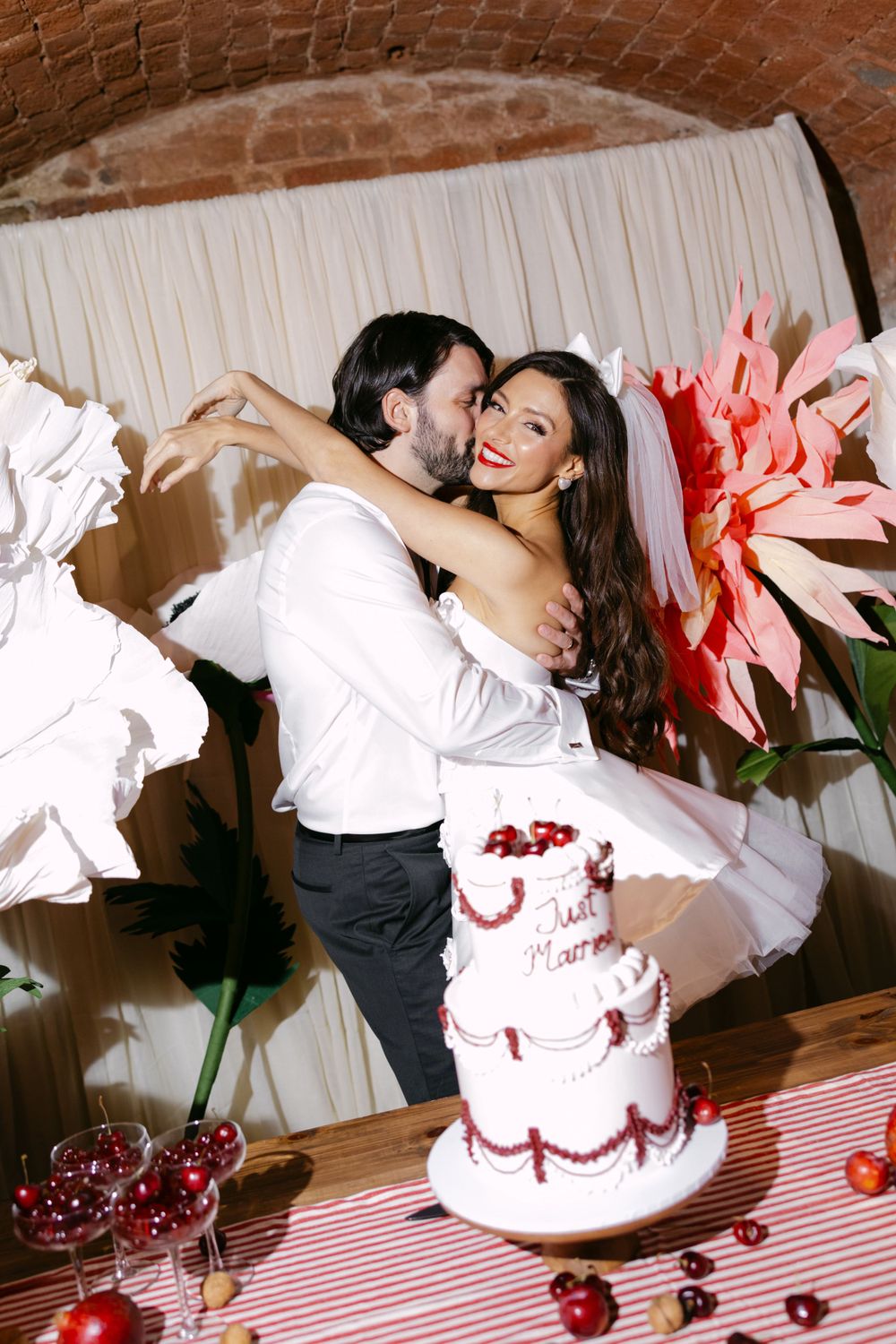 Wedding cake cutting sequence showing playful moment between couple at reception with brick wall background.