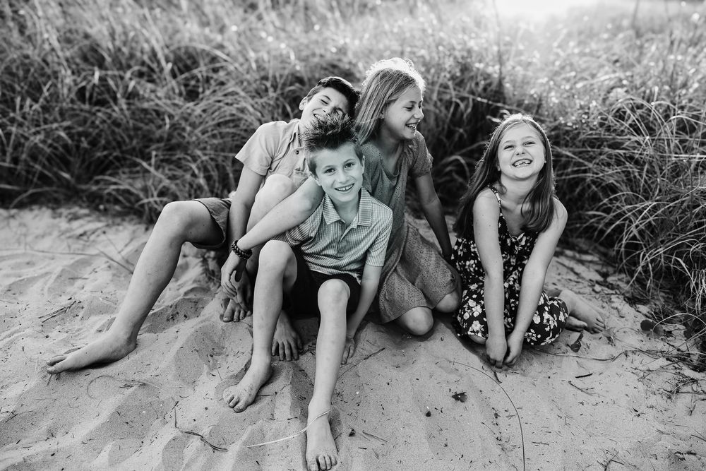 People lying on sandy beach near grass during summer day.