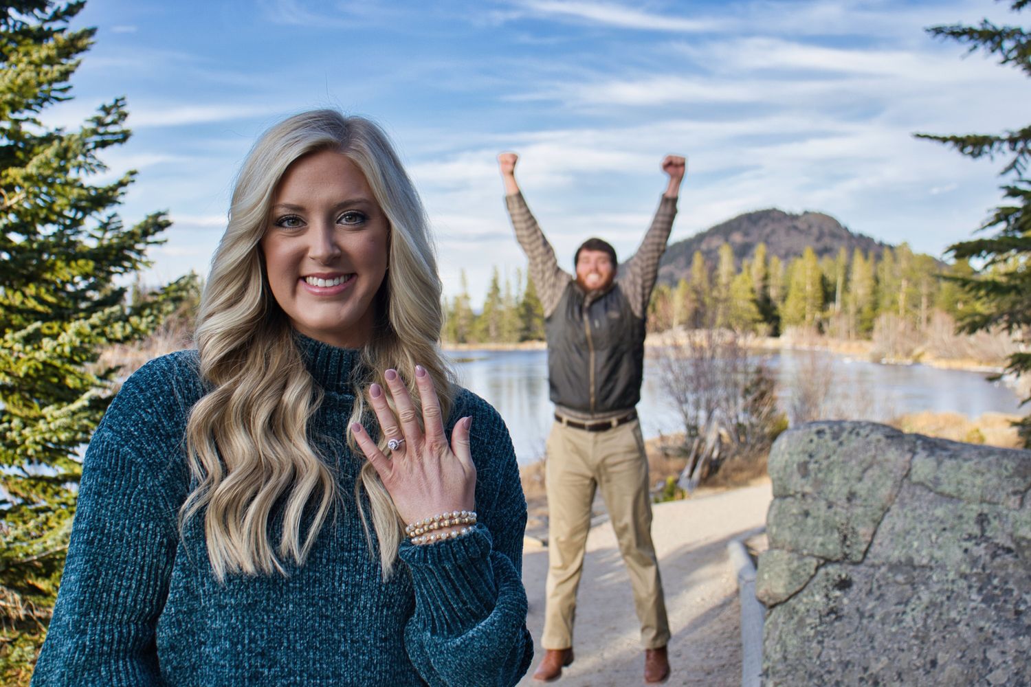 She said yes! Man jumping for joy behind his fiancé holding her hand and ring up. Pixcapades | The Rocky Mountain Proposal Photographer