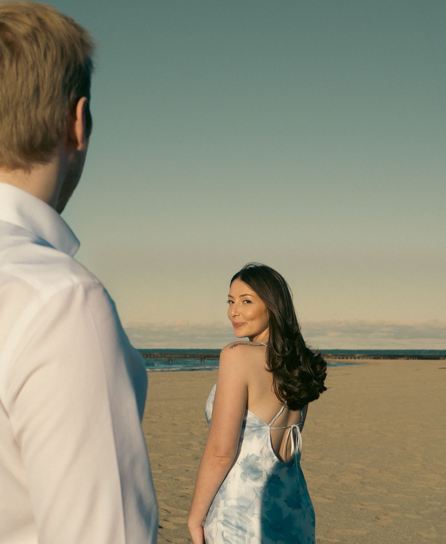 A romantic beach photoshoot with a couple against a sunset backdrop.