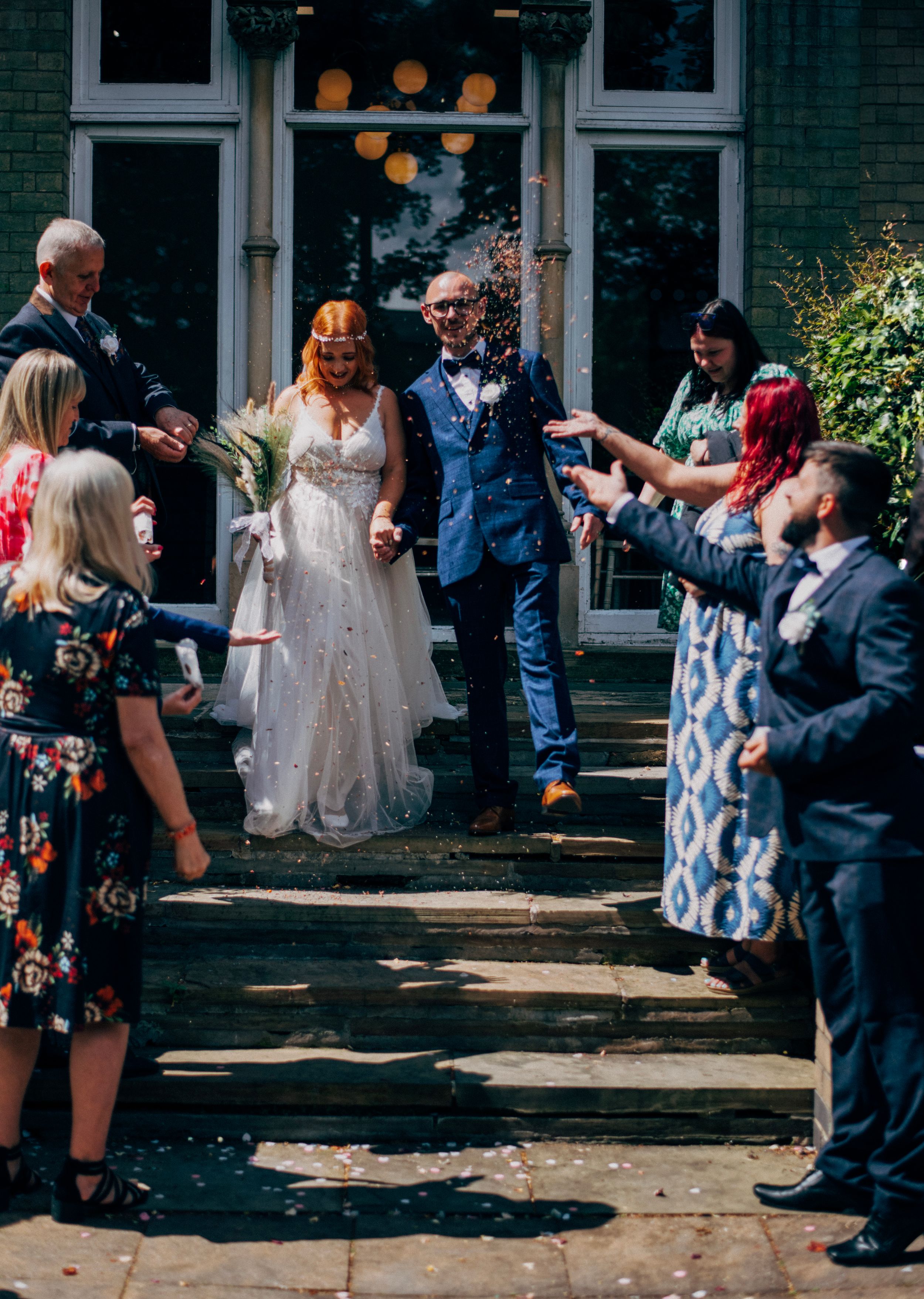 Wedding celebration on outdoor steps with guests throwing confetti at the newlyweds.