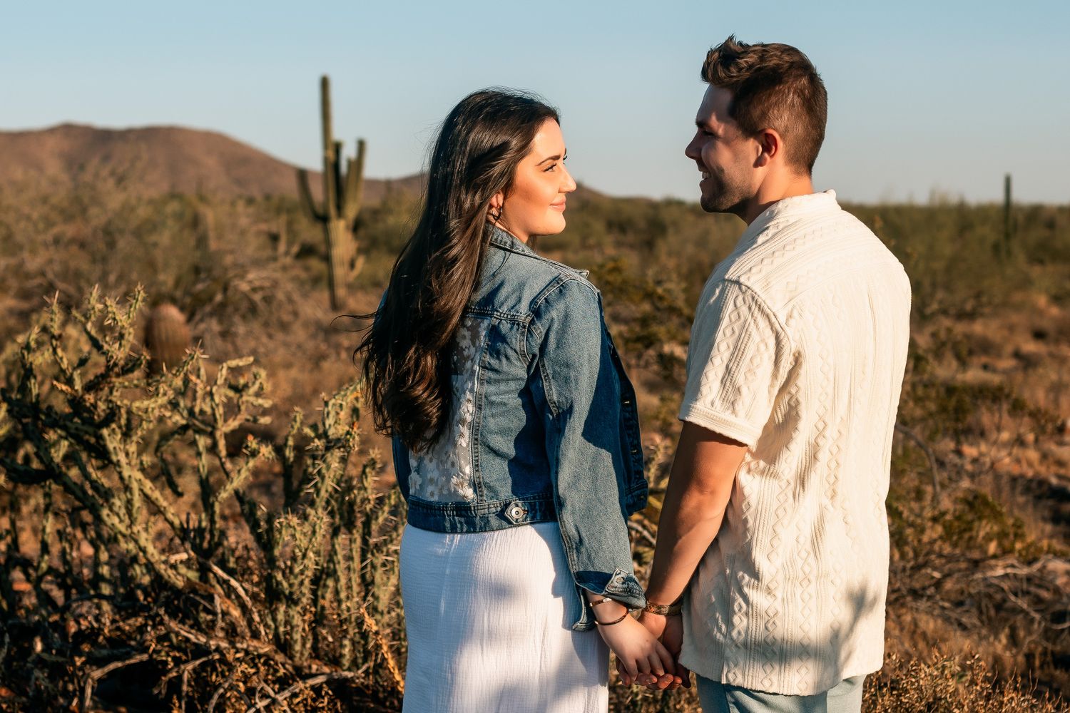 man and woman looking lovingly at each other smiling with golden hour sunset and a phoenix desert landscape background