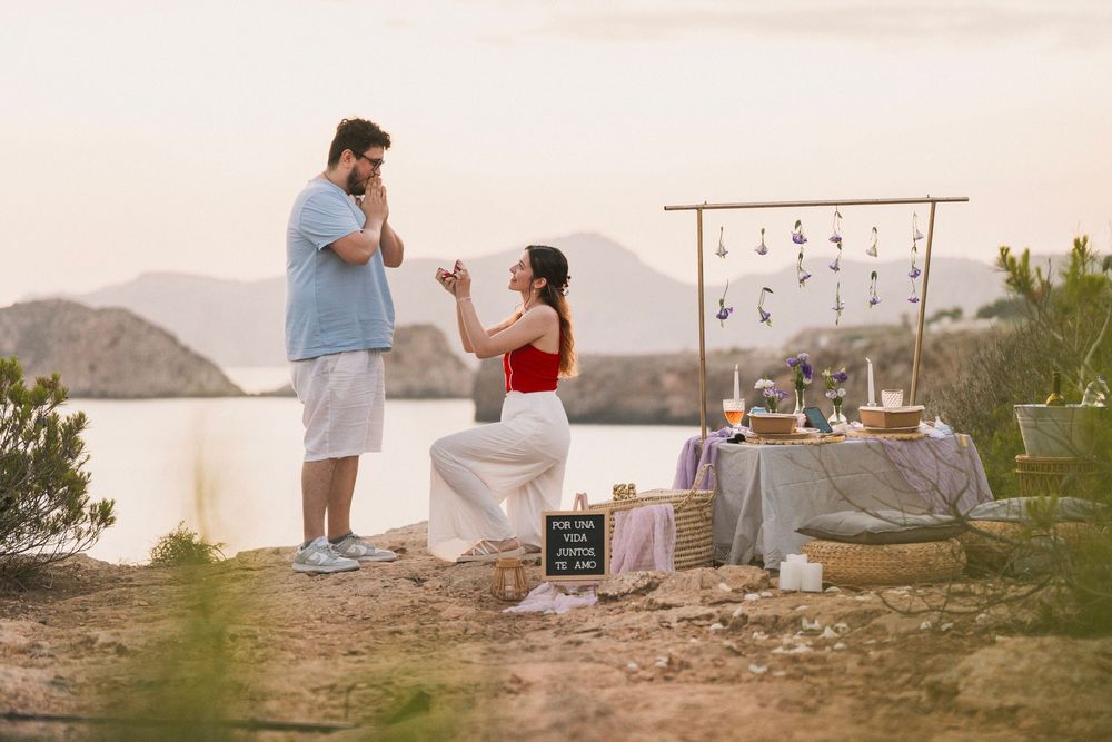 Pedida de mano junto al mar al atardecer, con la pareja en la playa, en una imagen de fotografía romántica en Mallorca.