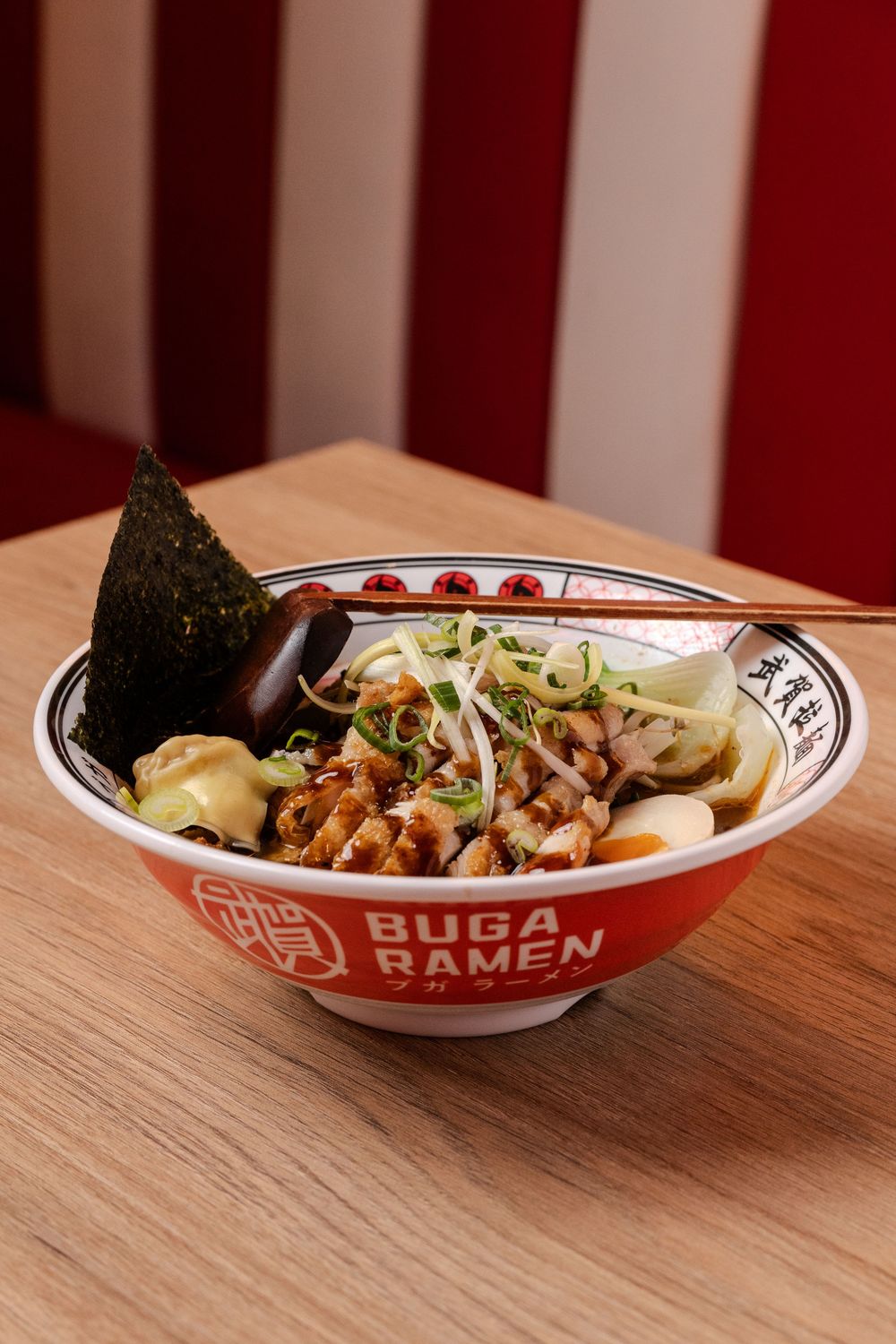 Bol de Buga Ramen con fideos, carne, cebolla verde y nori sobre mesa de madera, captado en una sesión de fotos gastronómica en Mallorca.