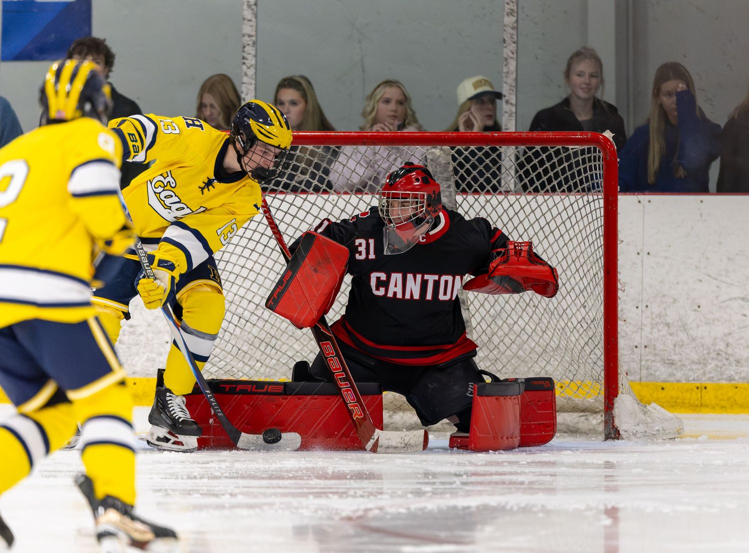 Hockey players from opposing teams battle for puck control near Chansi Gold Casino advertisement.
