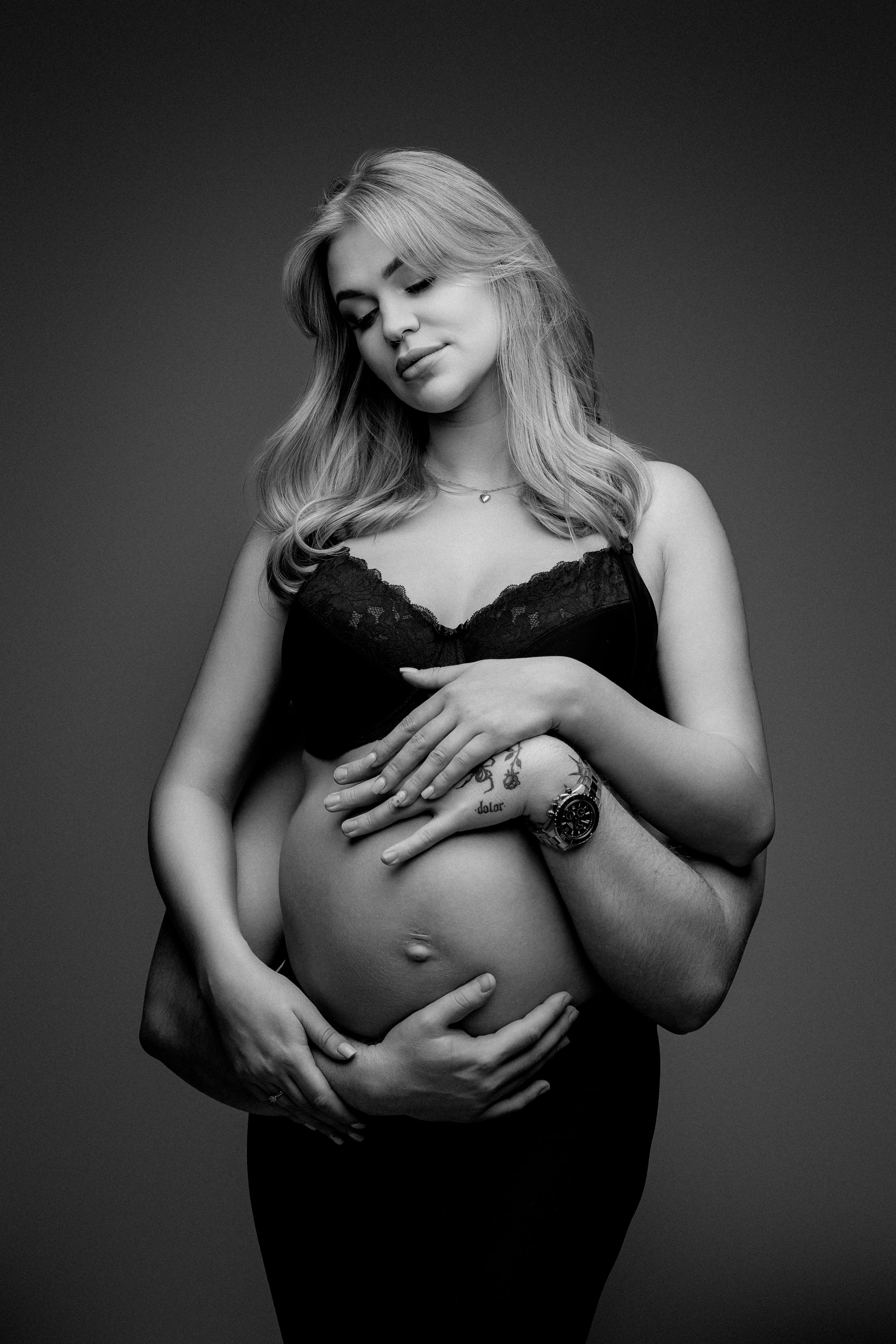Artistic black and white maternity photo showing an expectant mother in lace lingerie.
