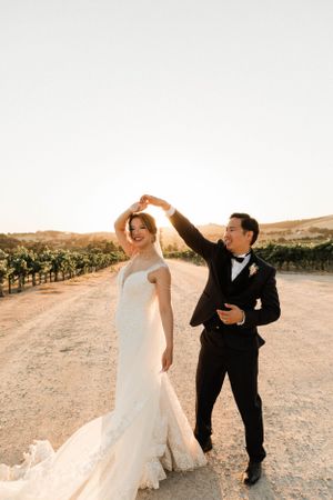 Asian bride and groom dance in front of the sunset after getting married in Paso Robles California at Cass Winery.