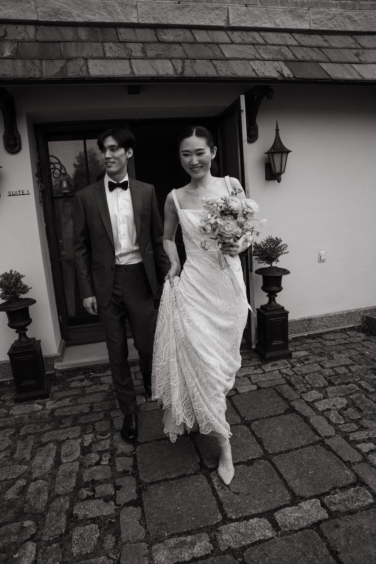 Black and white photo showing hands with corsage embracing from behind.