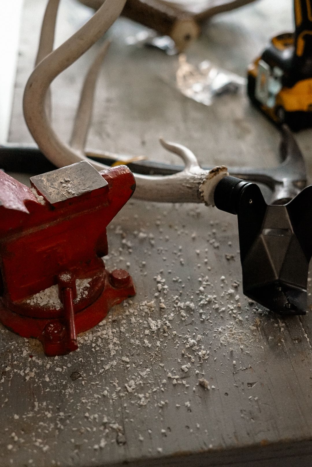 Close-up of antler being cut with red tool on workshop surface.