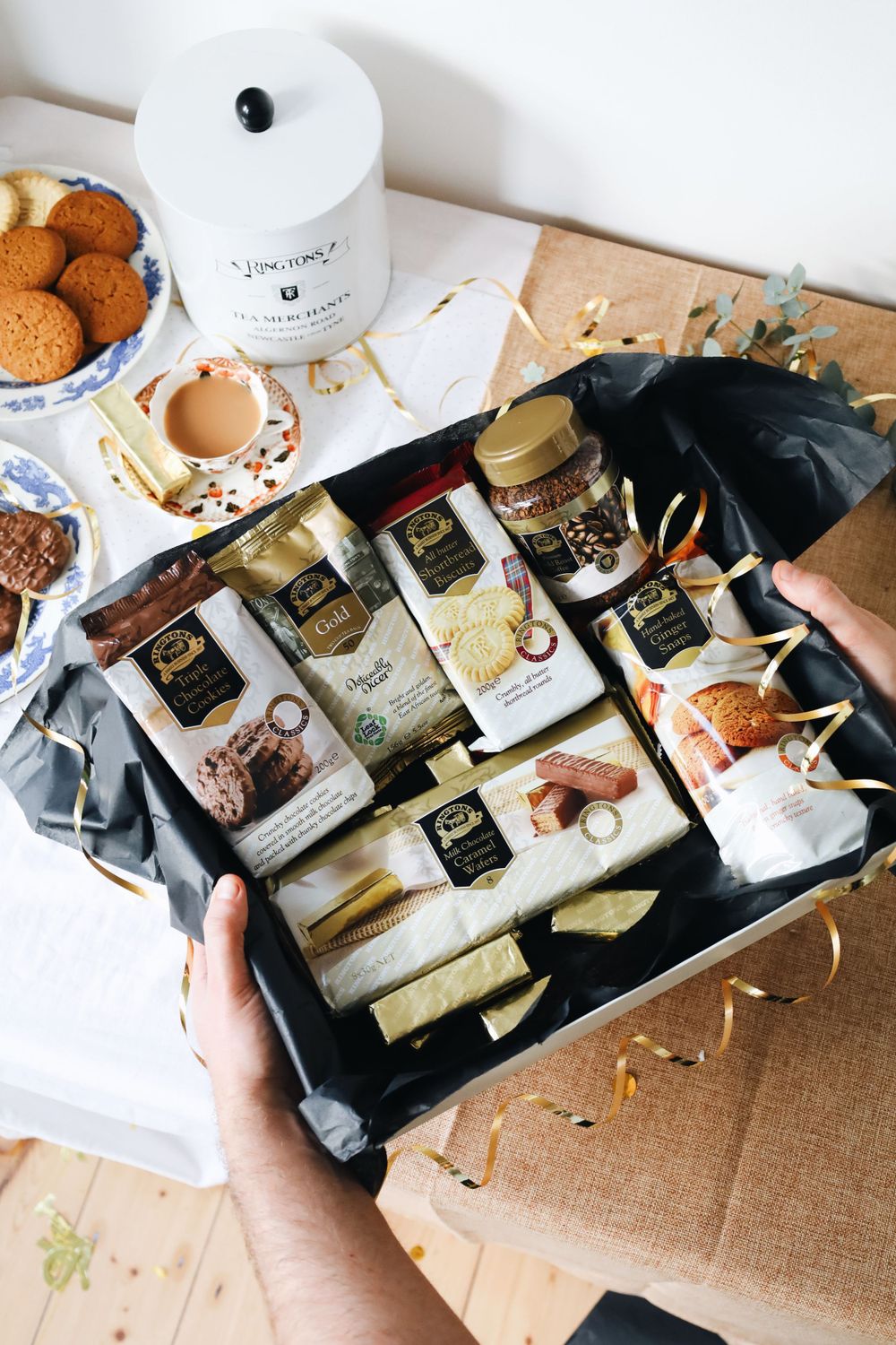 Gift box filled with assorted tea packages and treats being displayed.
