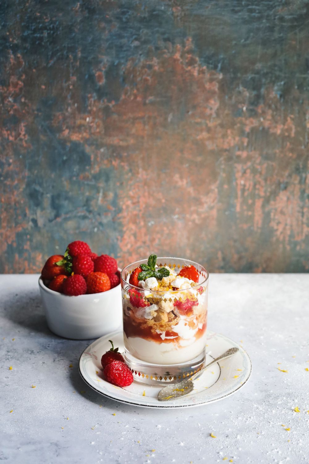 Elegant dessert parfait with fresh raspberries and cream on a white plate.