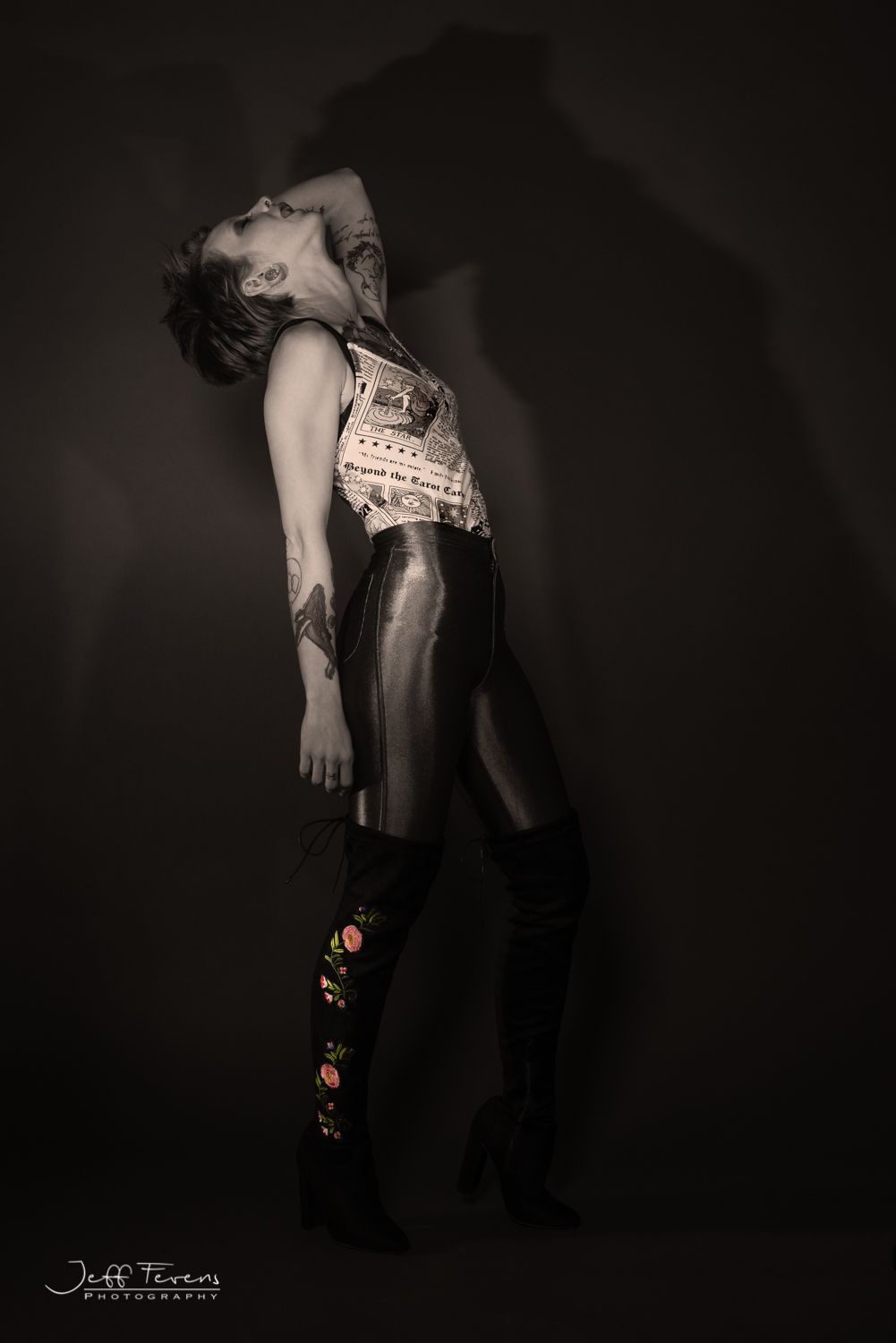 Desaturated image of woman standing in studio with her head thrown back.