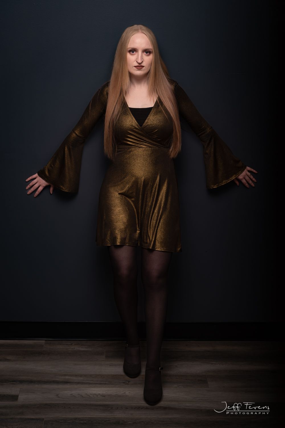 Woman with long blond hair in gold dress in studio.