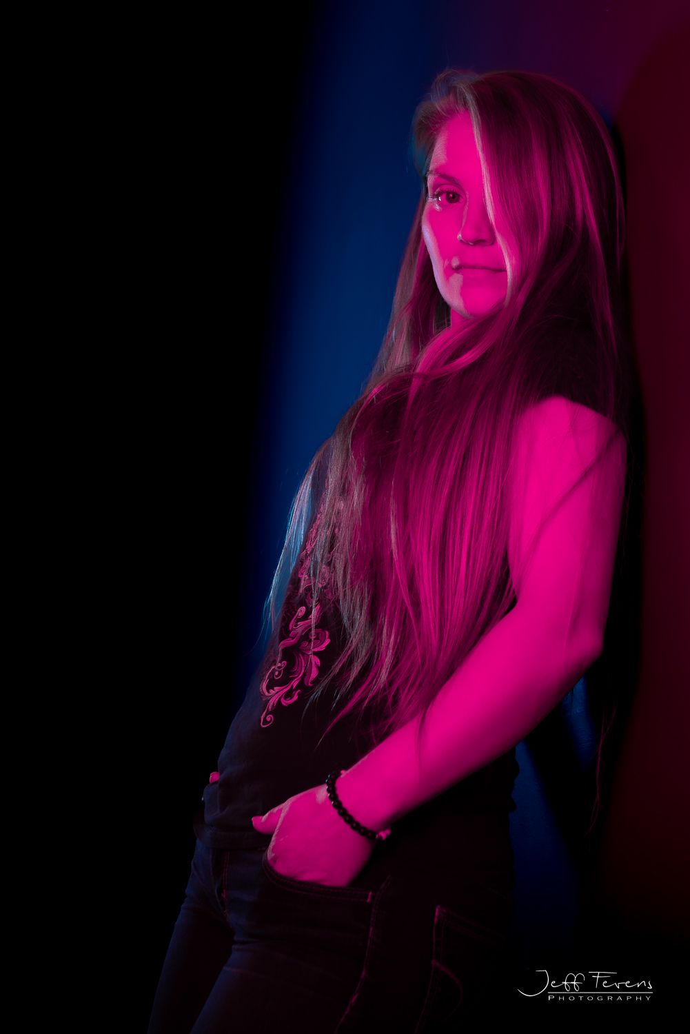 Woman with long blond hair leaning against the wall in studio.