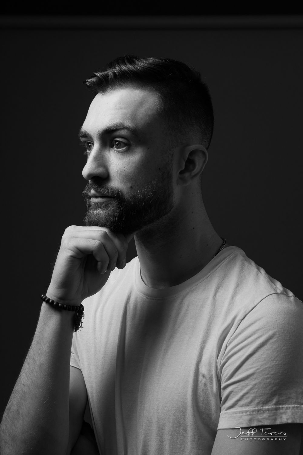Black and White of a side portrait of a male with chin on fist.