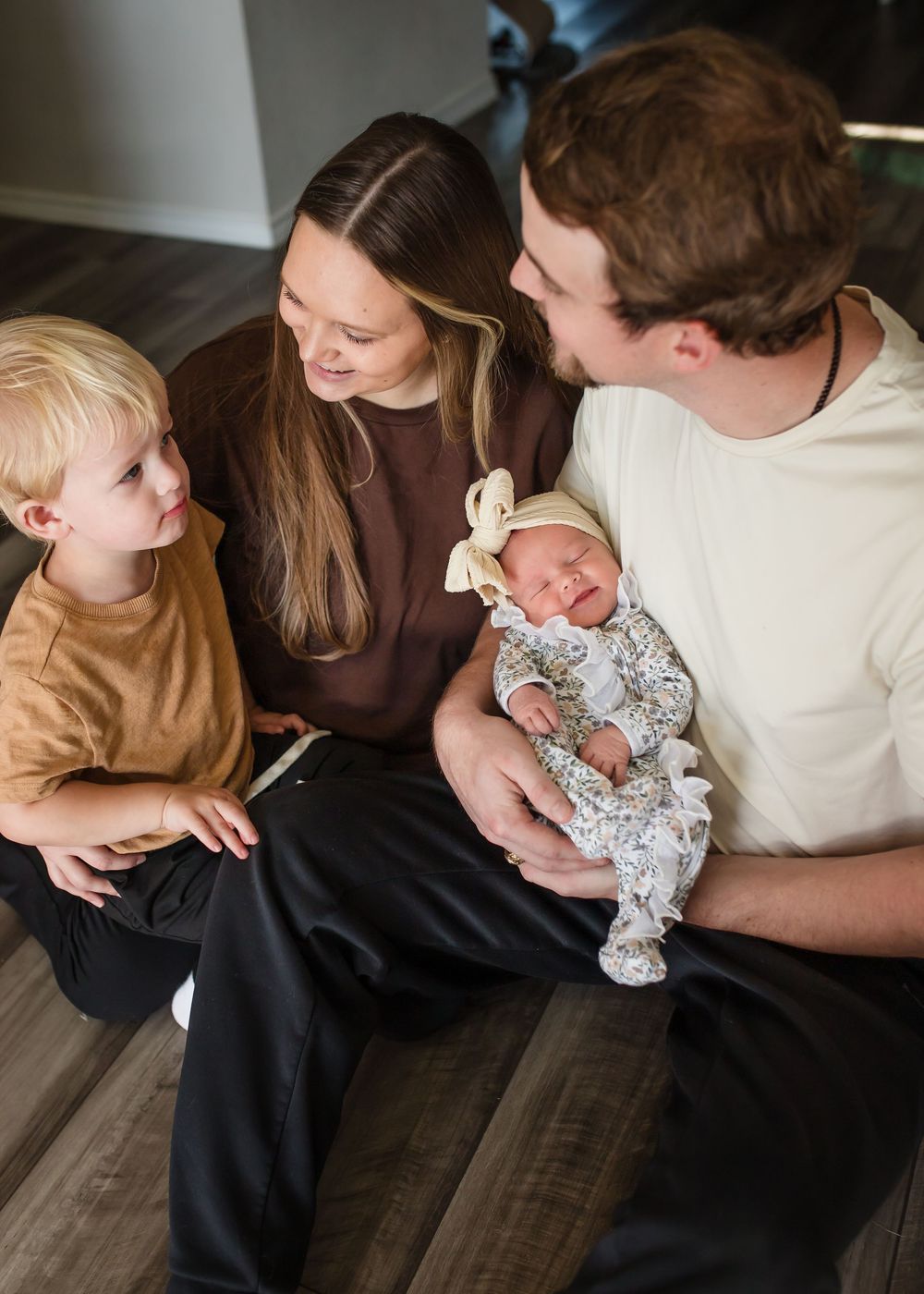 A sweet moment showing a baby in a floral outfit being held and admired by her family.