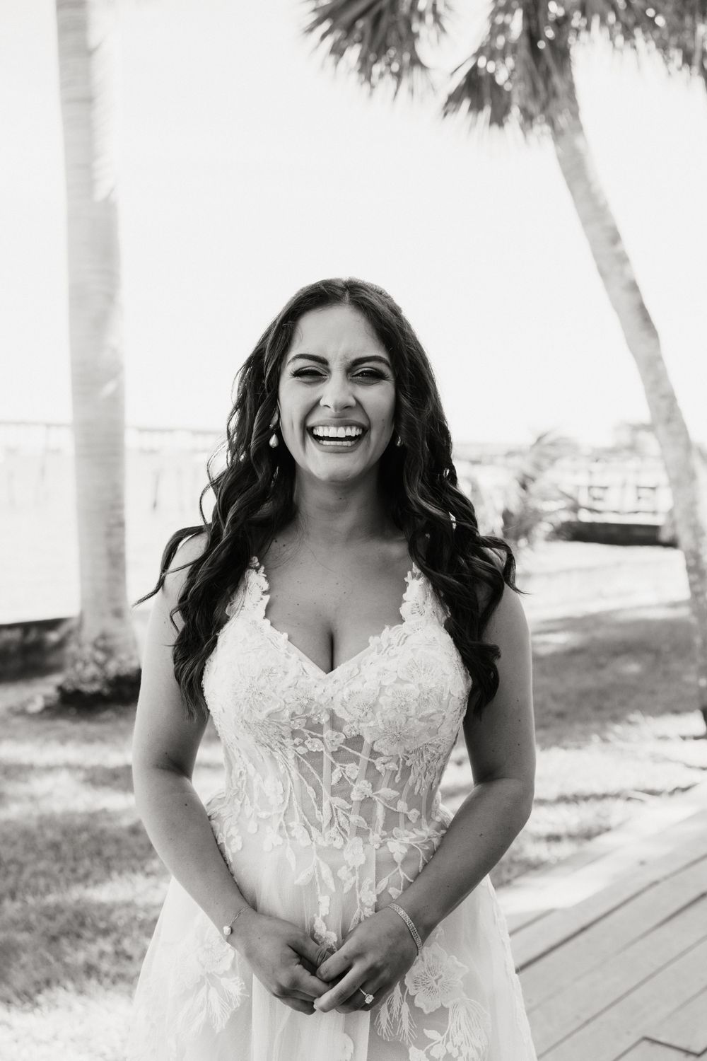 Black and white portrait of a radiant bride in a lace wedding gown with palm trees in background.