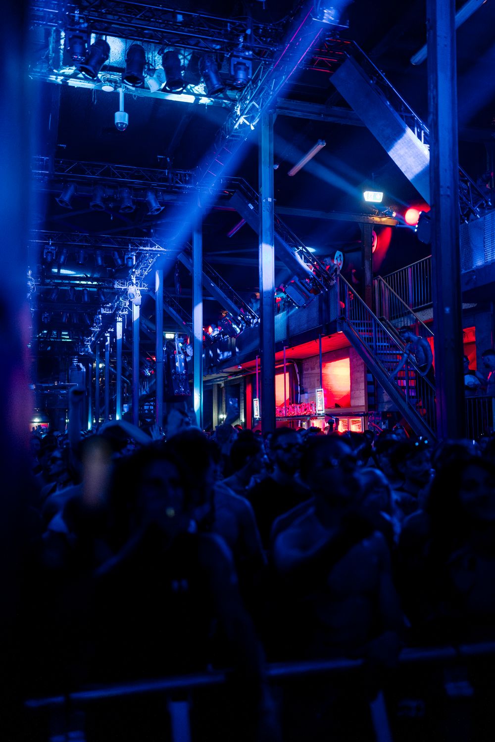 Spacious nightclub venue with dramatic blue and red lighting effects.