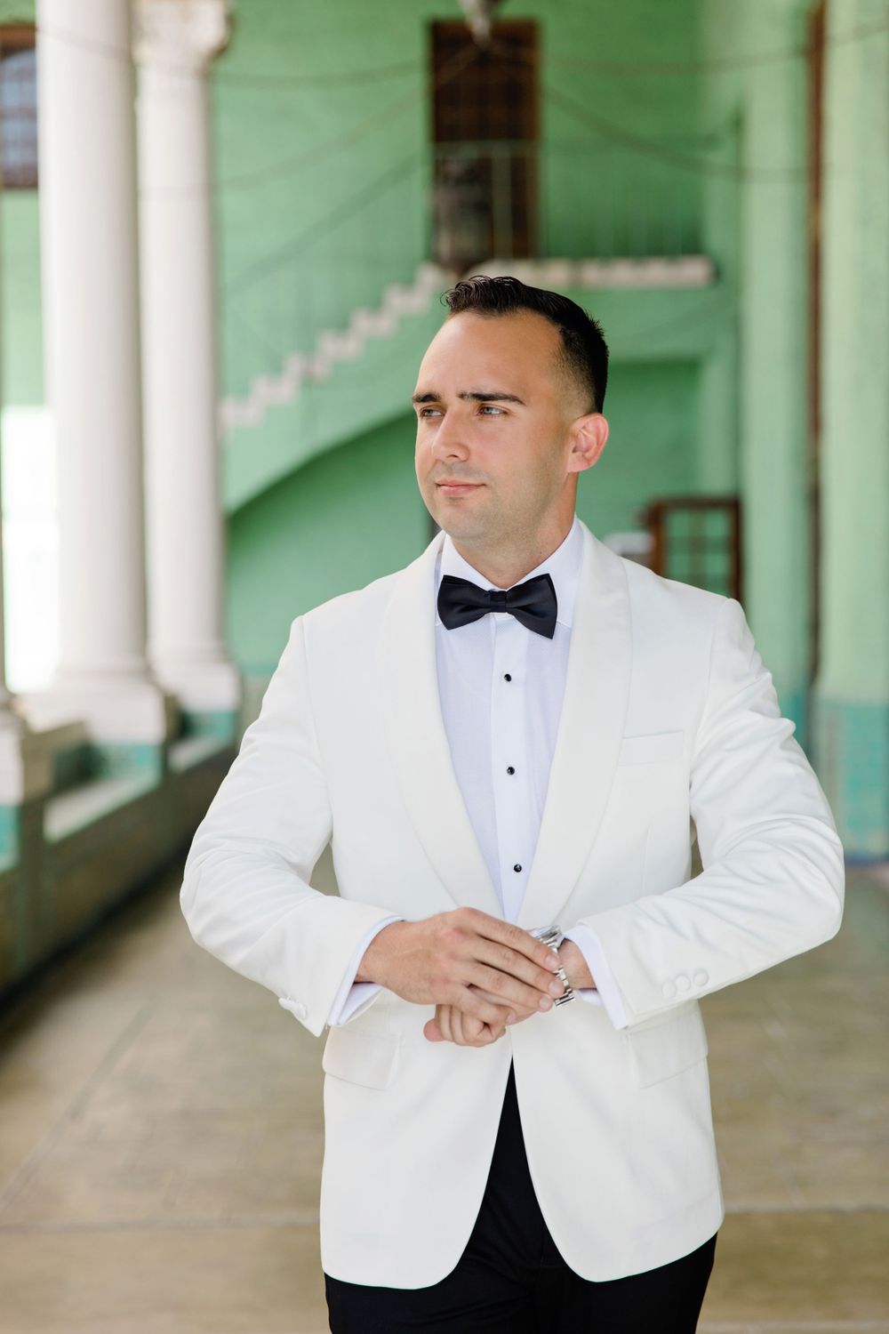 A formal white tuxedo jacket with black bow tie photographed against a green architectural backdrop.