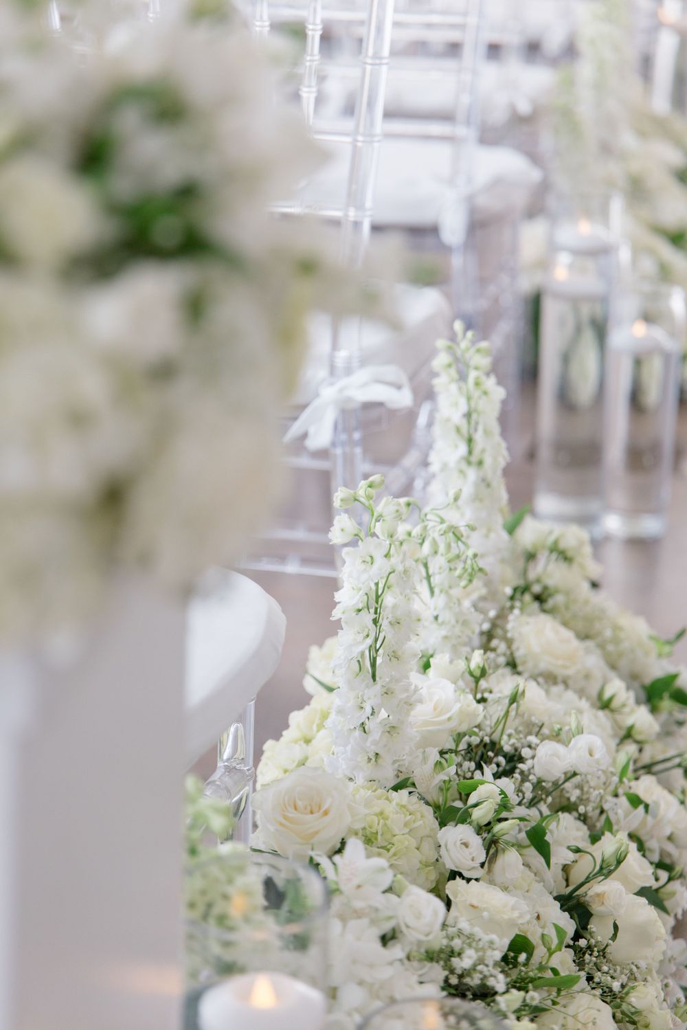 Close-up of white roses and delicate flowers in an elegant wedding table arrangement.