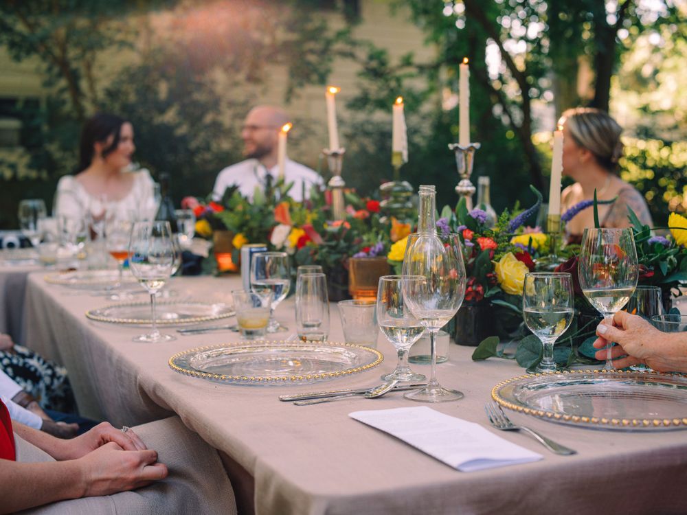 An elegantly set outdoor dinner table with candles, wine glasses, and floral decorations.
