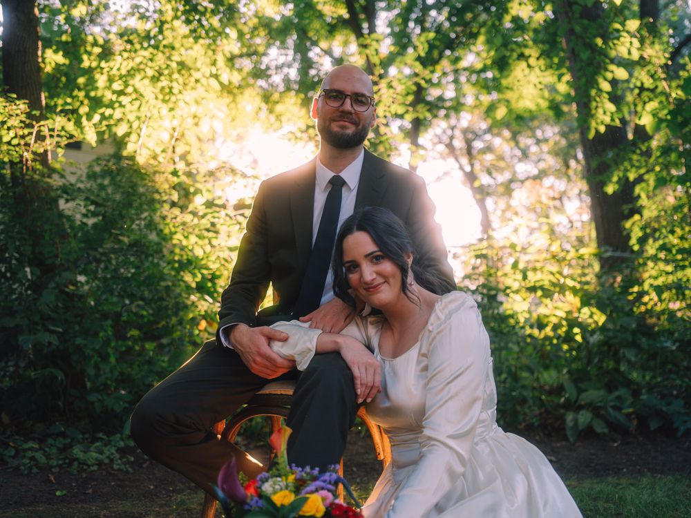 A candid wedding photo showing laughter and joy in a sunlit garden setting.