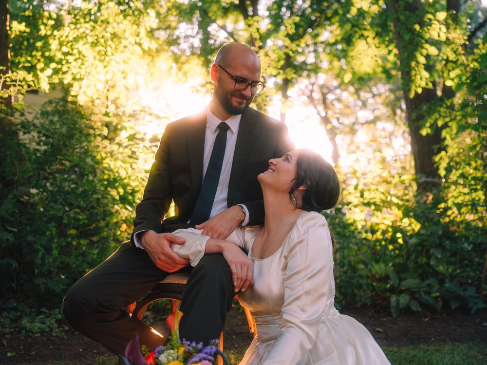 A joyful wedding moment captured in a garden with warm sunlight creating a beautiful backlit effect.