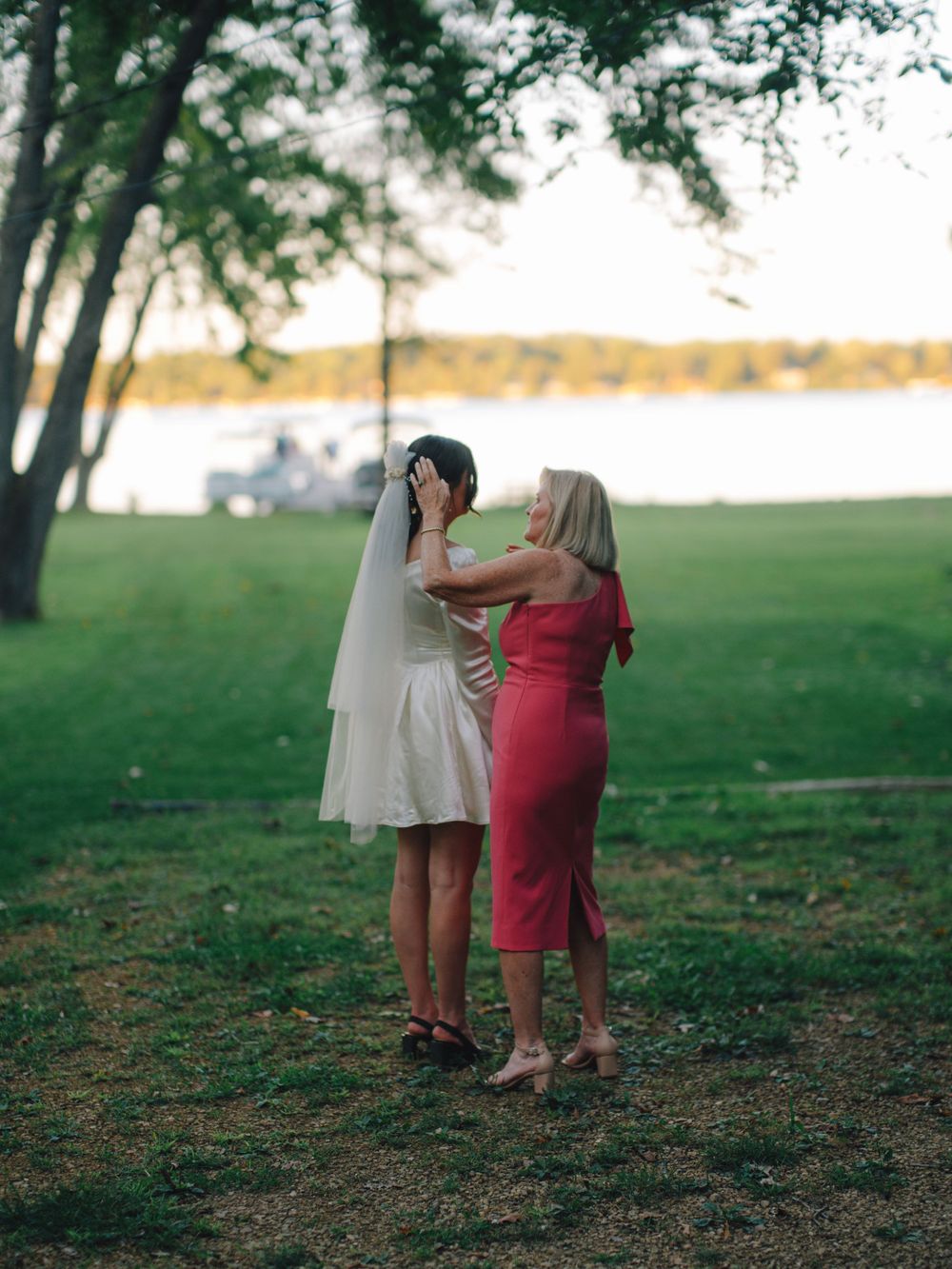 A tender moment shared between two people by a lakeside as sunlight filters through trees.