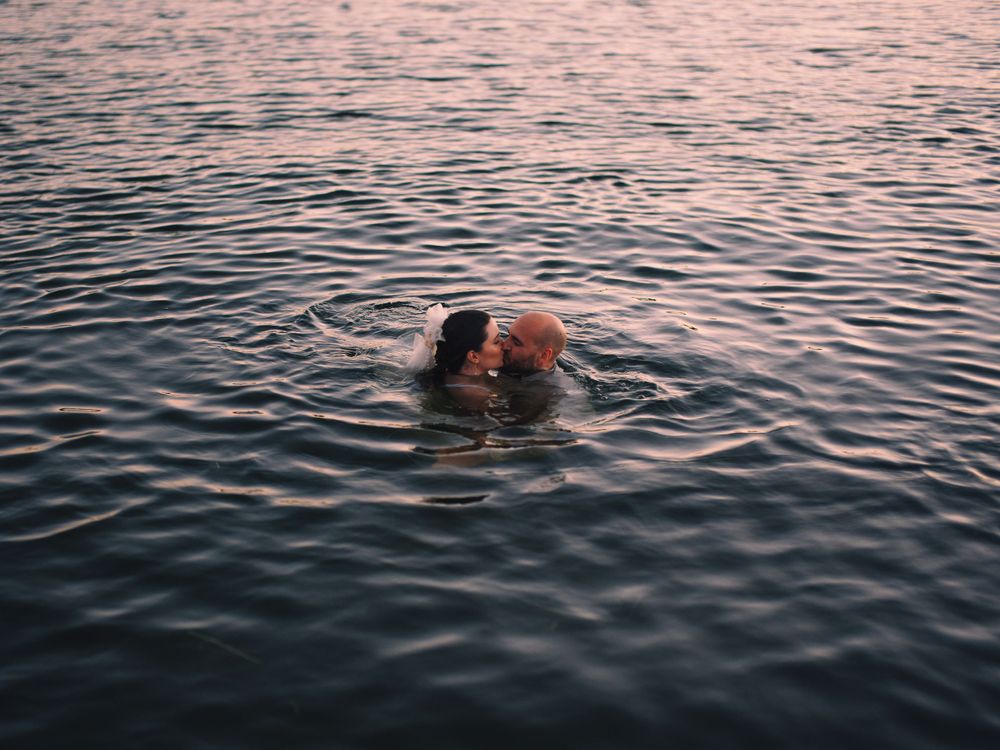 Two silhouettes swim in rippling water during a romantic sunset moment.