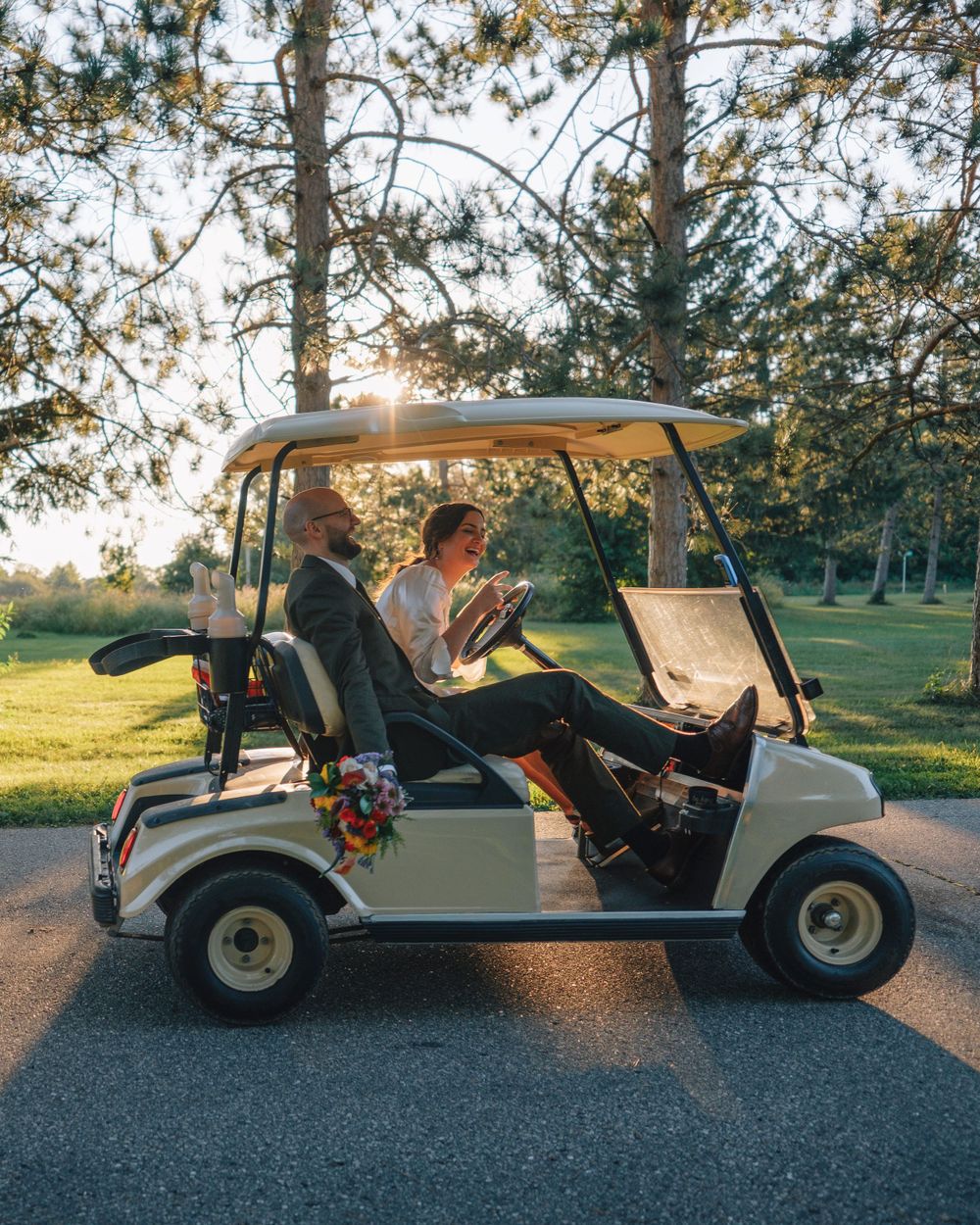 A bride and groom share a moment in a golf cart during sunset.