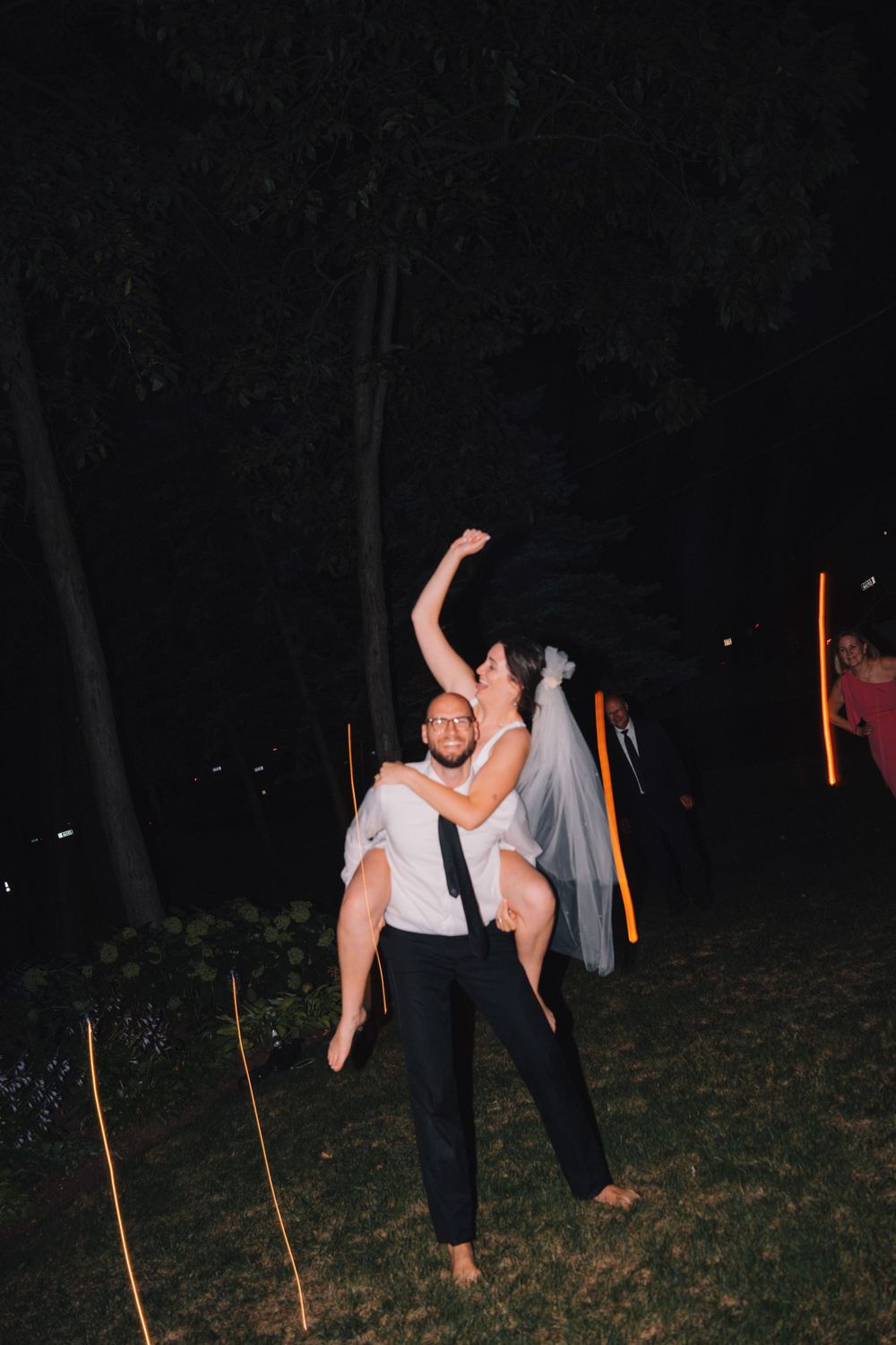 A joyful dance moment captured at night with illuminated garden lights in the background.