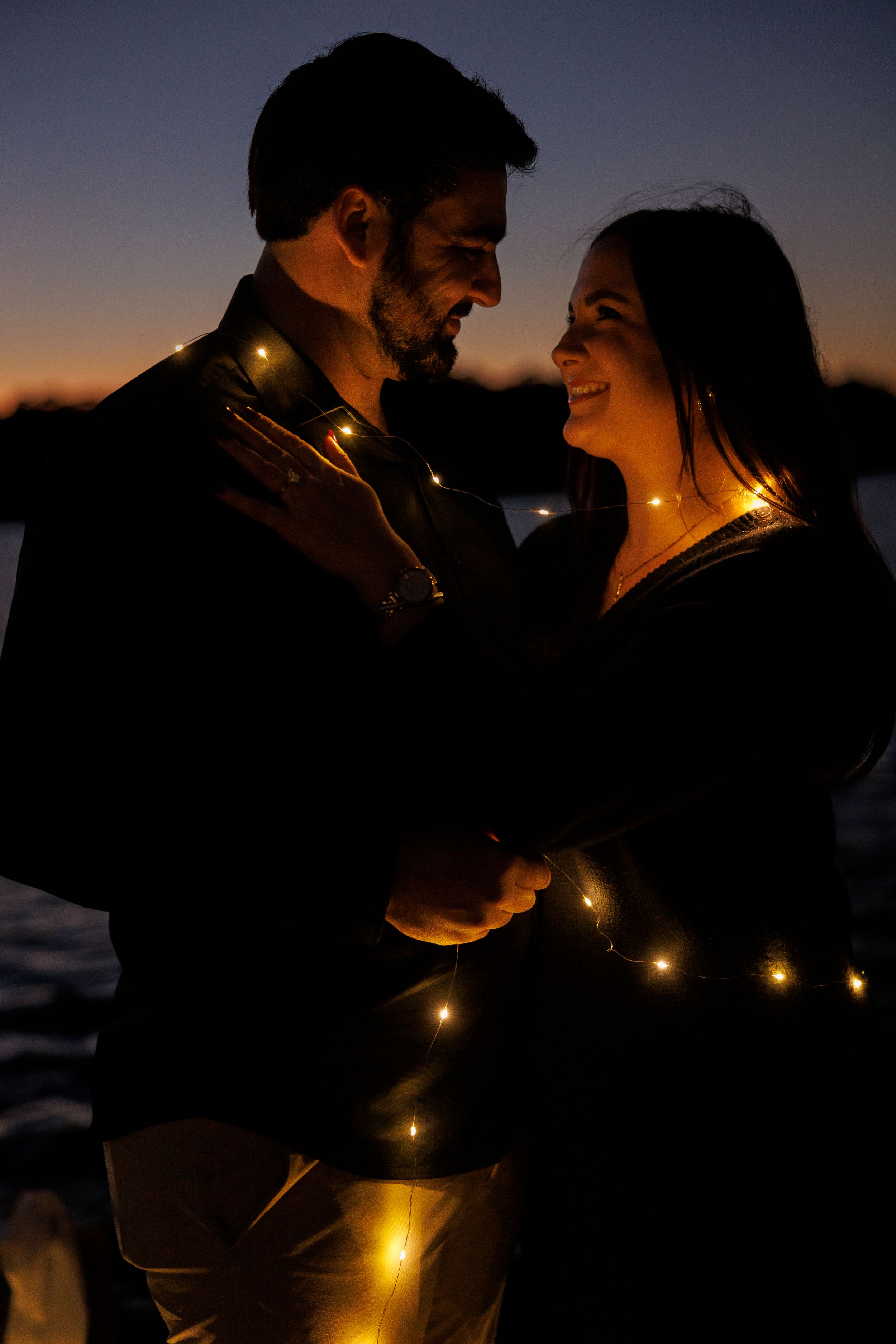 Romantic silhouettes illuminated by string lights at twilight creating an intimate atmosphere.