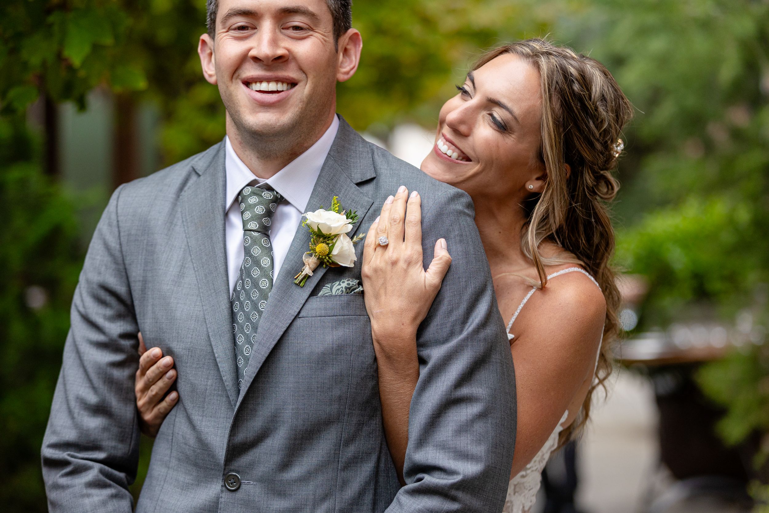 A joyful couple shares a candid moment together on their wedding day in a lush garden setting.