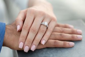 Close-up of hands with an engagement ring featuring a classic solitaire diamond.