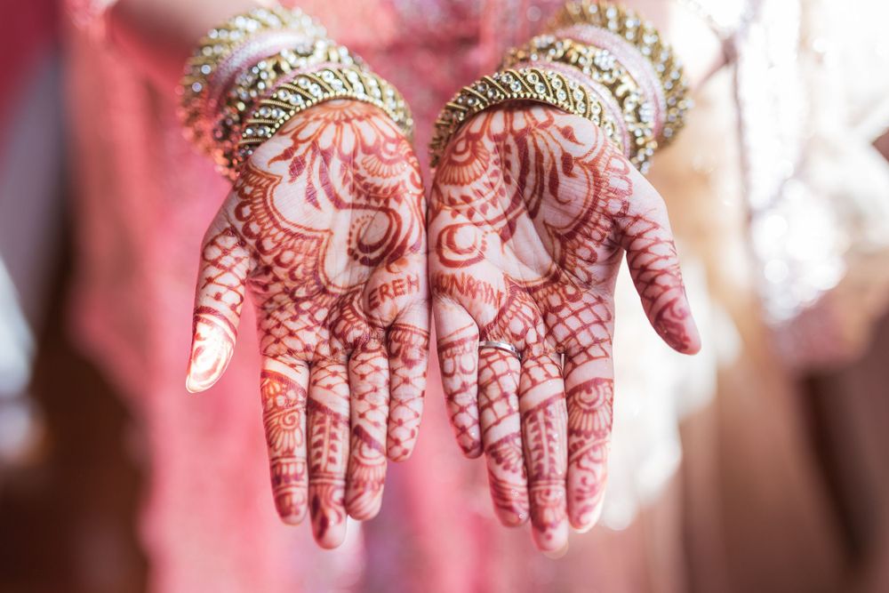 Intricate henna mehndi designs adorned on both palms with traditional Indian bridal jewelry.