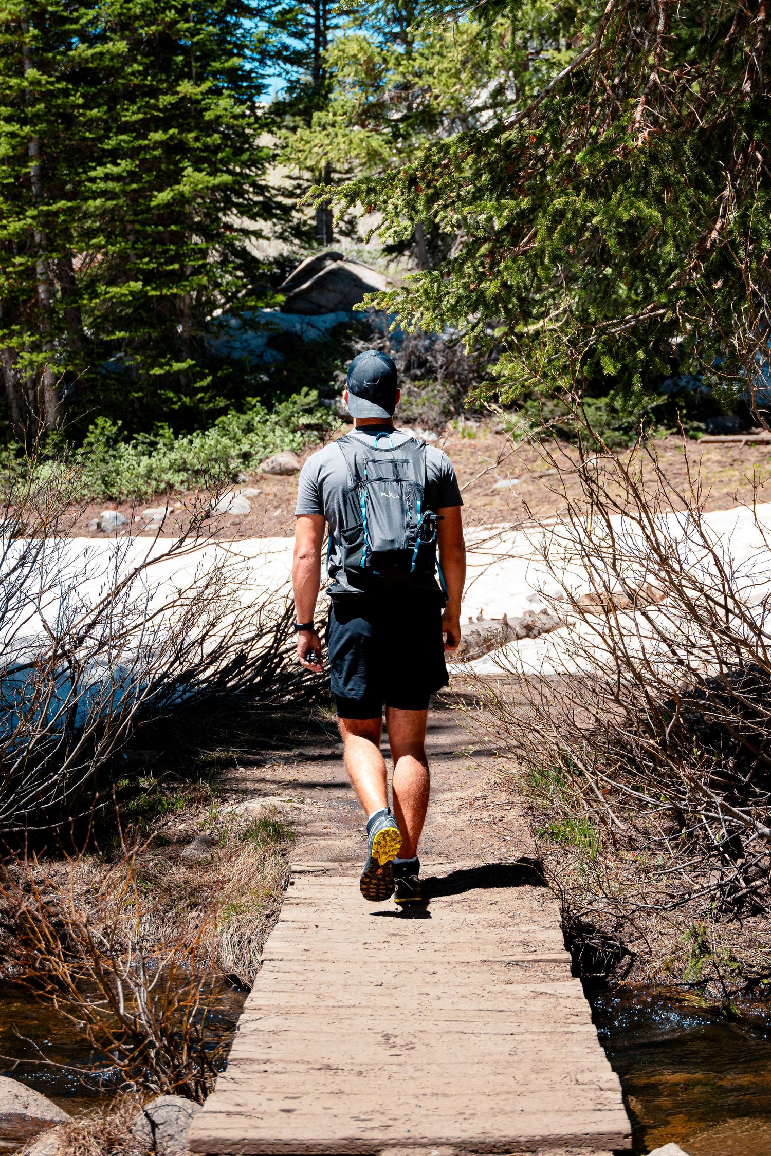 Hiker walking on wooden boardwalk through snowy forest trail.