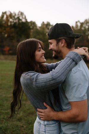 Couple in casual attire embracing outdoors during autumn sunset.