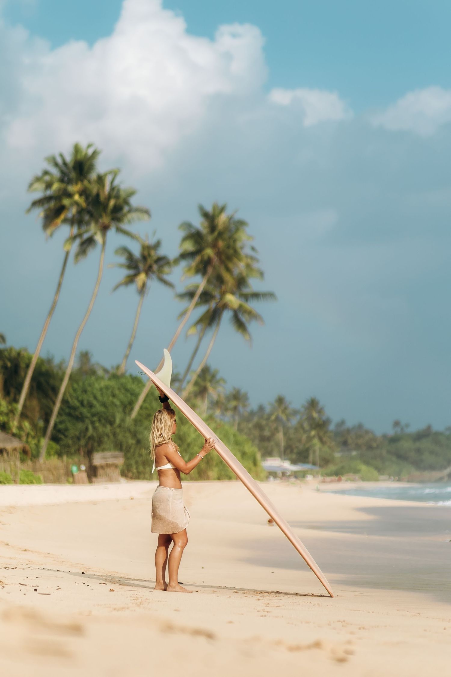 Person doing yoga poses on tropical beach with palm trees.