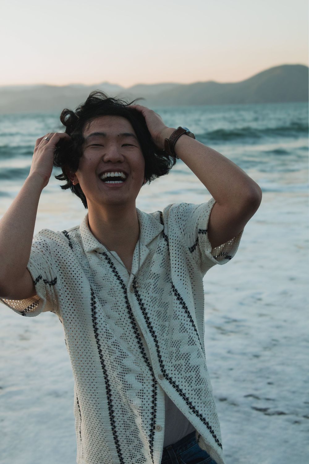 Candid laughter and carefree moment captured at beach during golden hour.