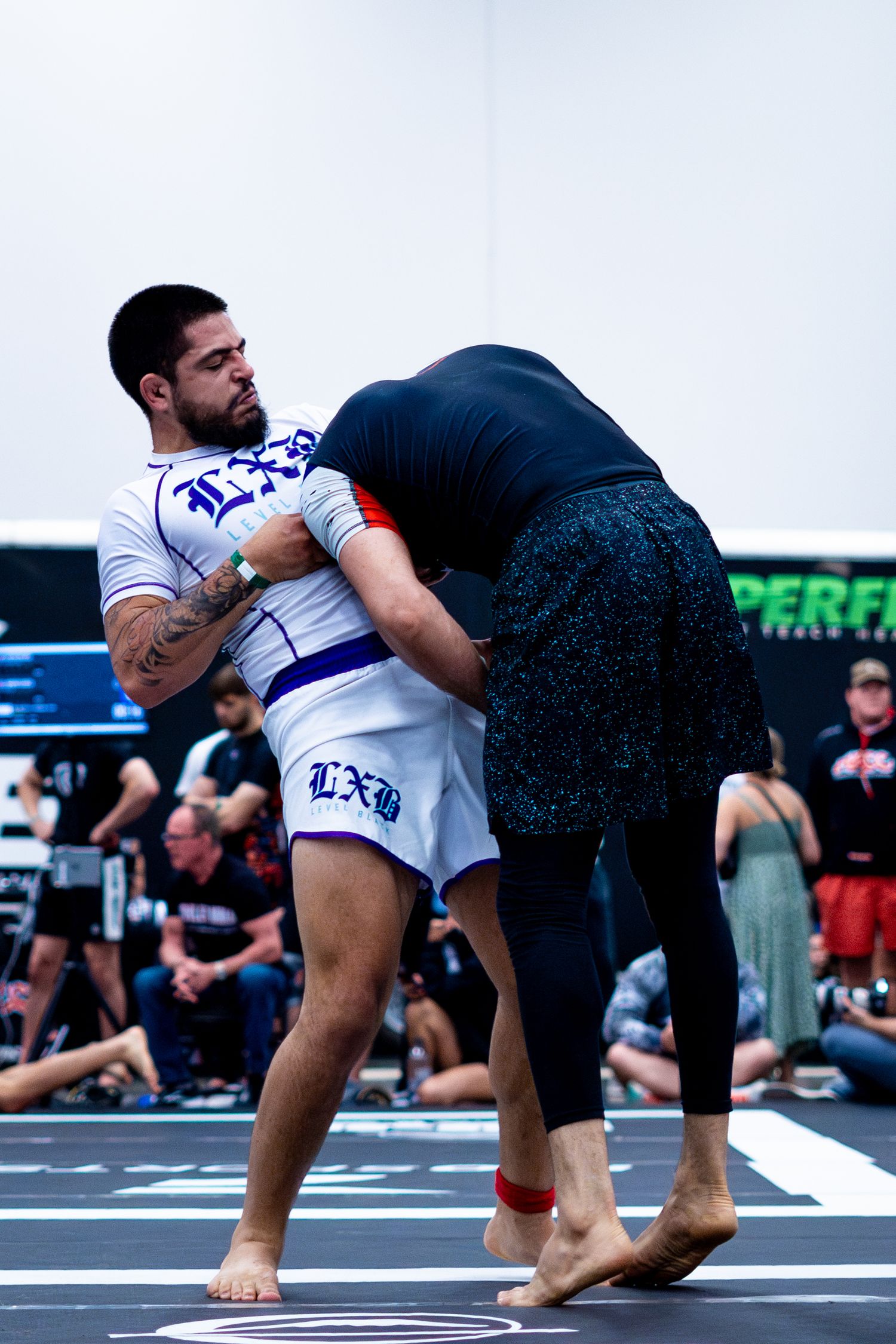 Two athletes engaged in a grappling match during a martial arts competition.