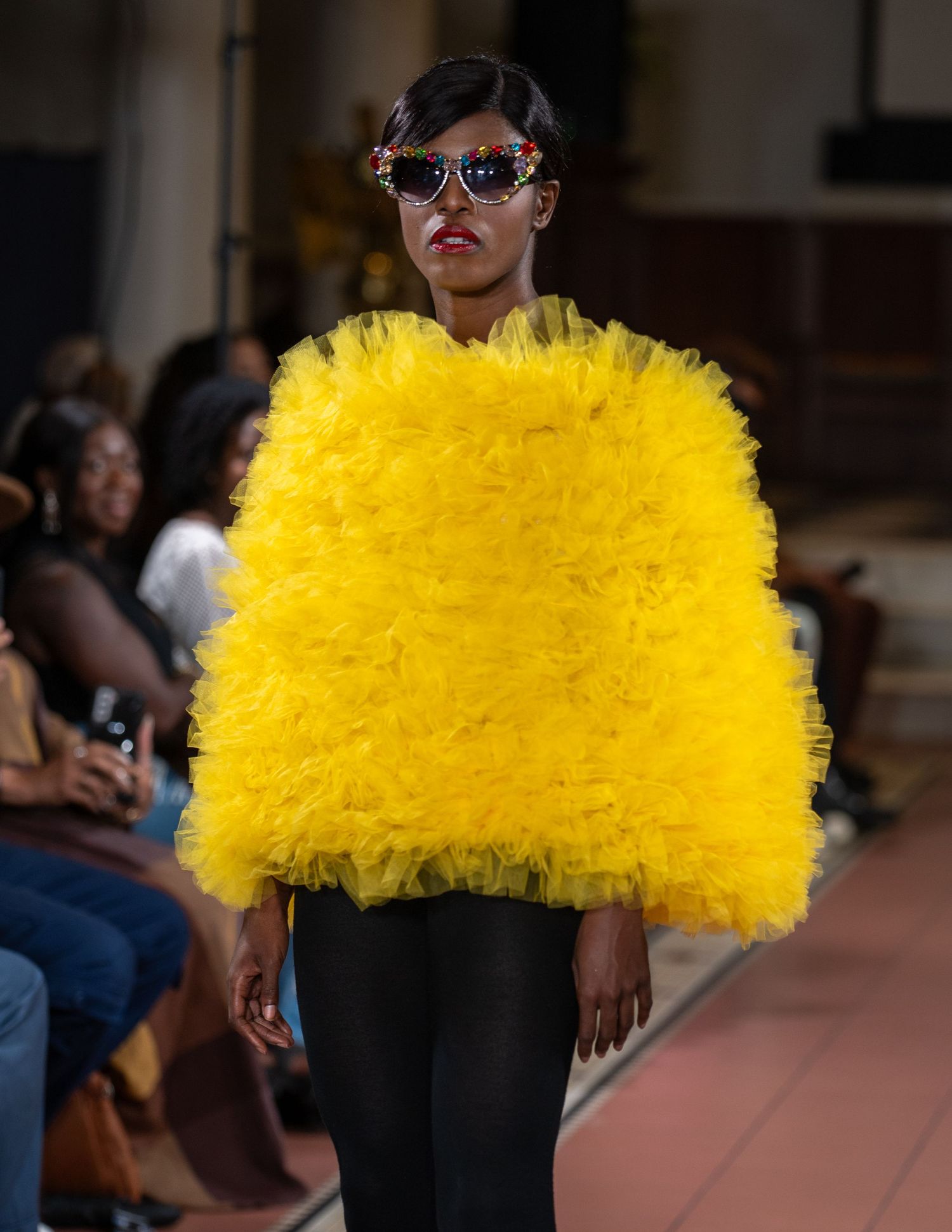 Bright yellow feathered top paired with black pants on fashion runway.