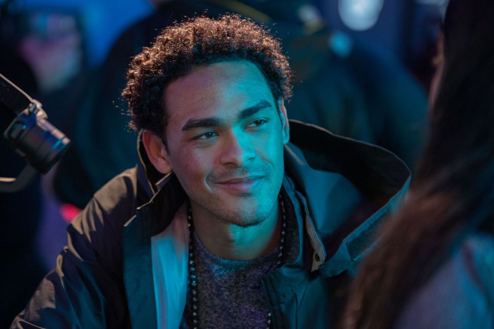 Person smiling in moody blue lighting at nighttime event.