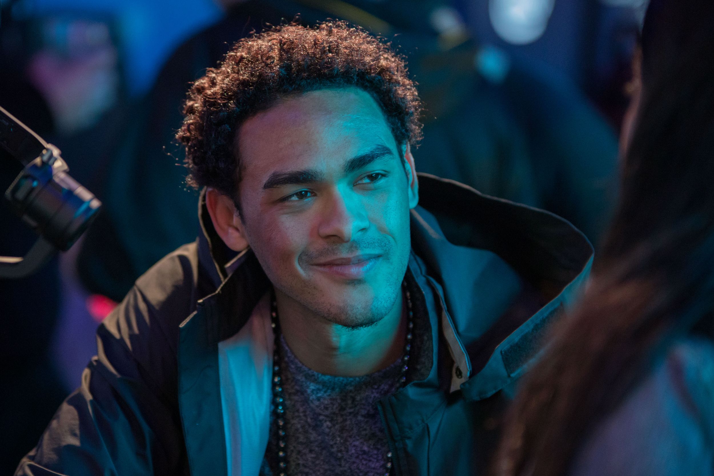 Person smiling in moody blue lighting at nighttime event.