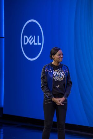Dell corporate event featuring presenter against blue backdrop with company logo.