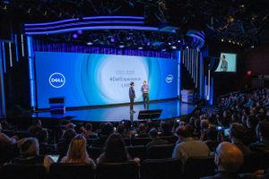 Wide shot of Dell conference presentation with large screen and audience in theater.