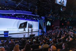 Large audience watches presentation on wide screen at Dell corporate event.
