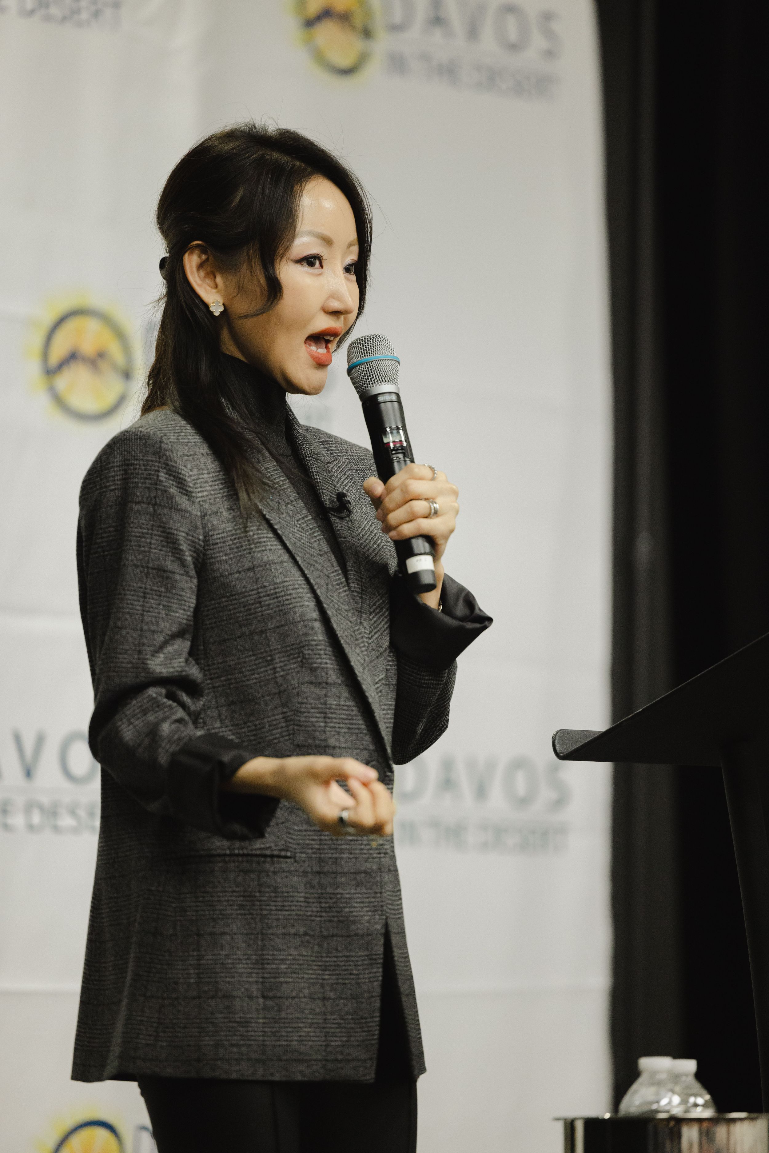 Speaker in gray blazer presenting at podium with Davos backdrop.