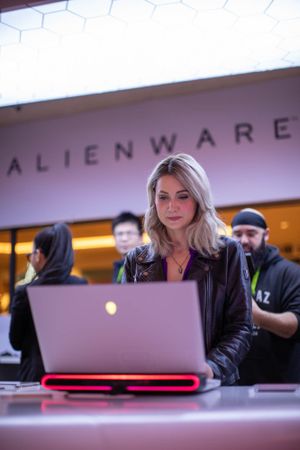Tech professional working on laptop at Alienware branded retail display.