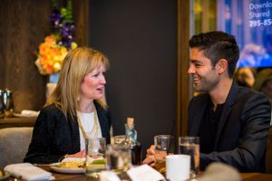 Two people enjoying conversation over drinks at an elegant restaurant dinner.