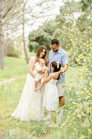 Family portrait in a spring meadow with yellow wildflowers.